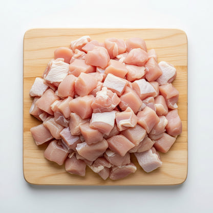 Diced raw chicken on a wooden cutting board with a white background